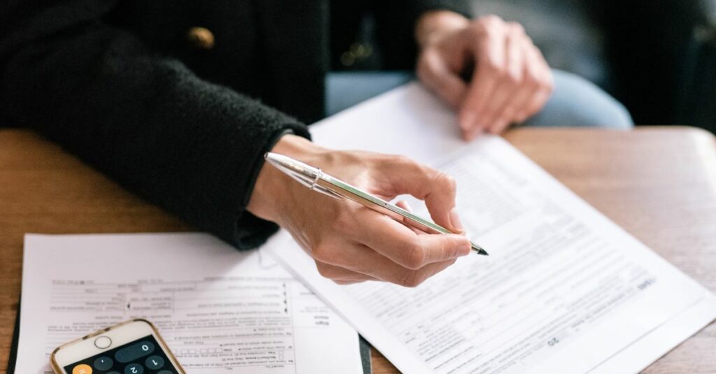 A woman reviewing financial documents with a calculator and glasses on a table.